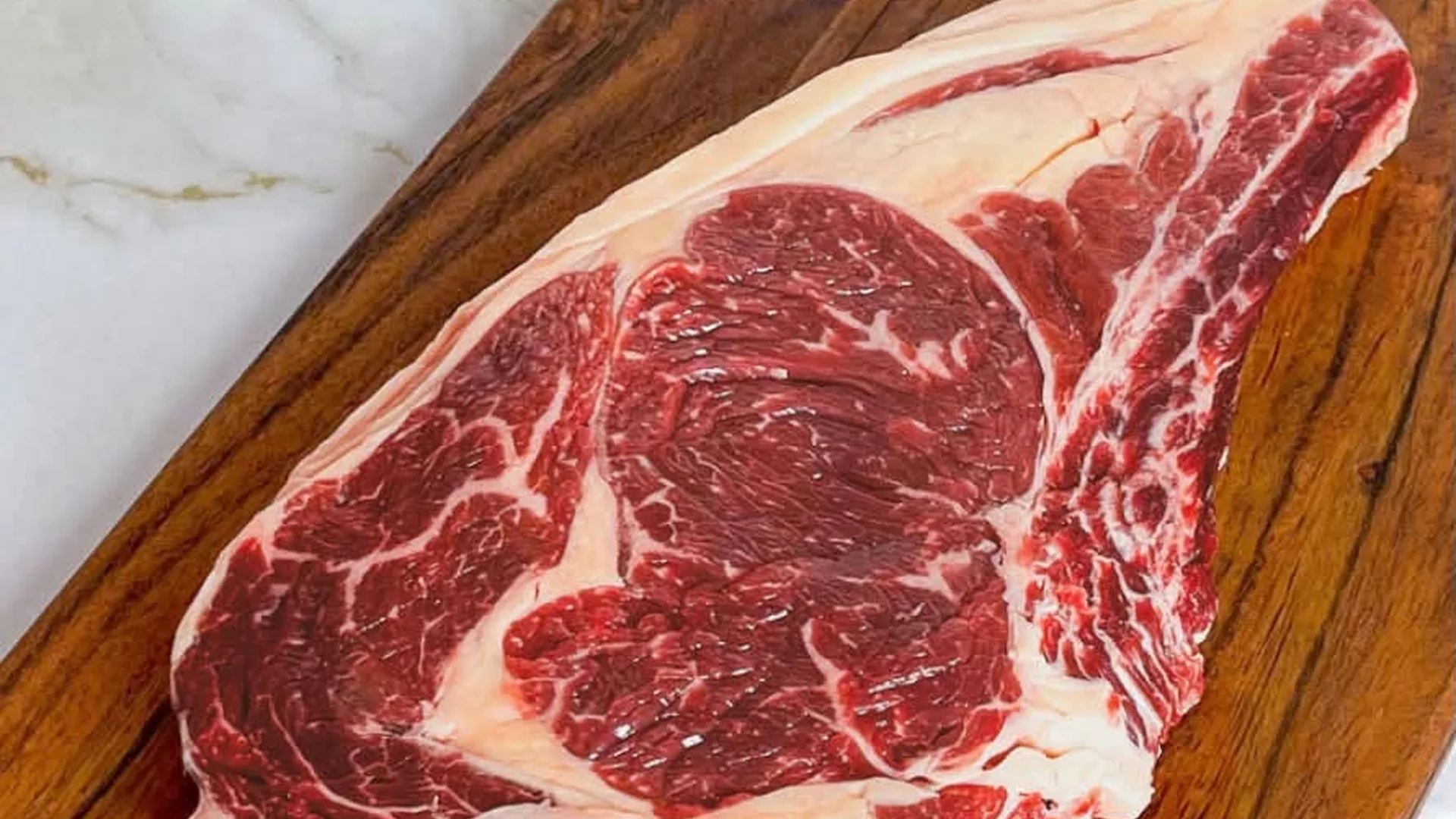 Côte de bœuf persillée présentée sur une planche en bois